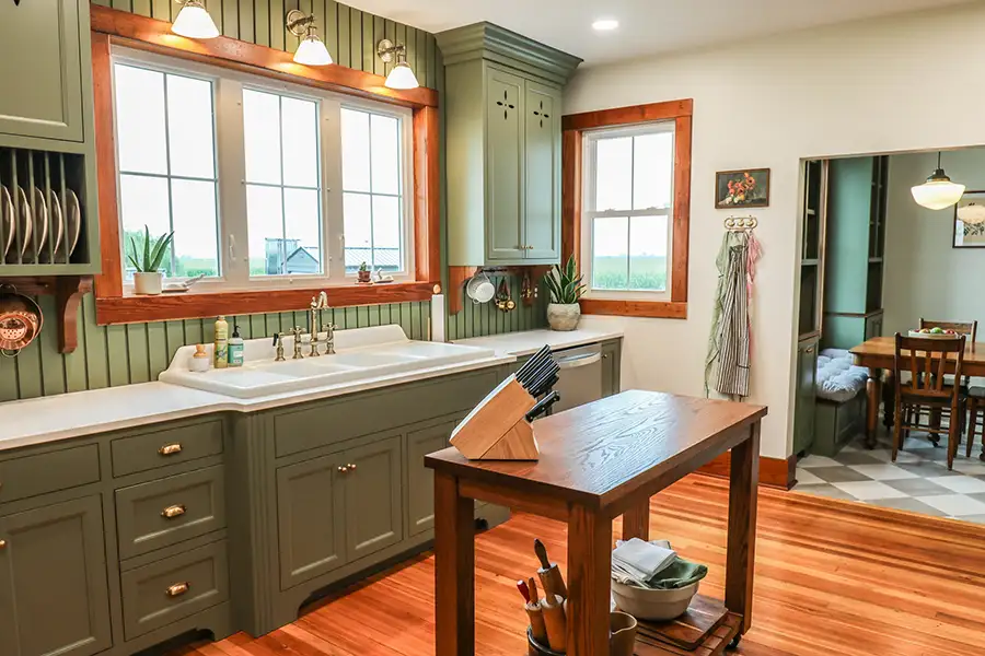 Gravel Lane Design Studio - beautiful farmhouse style kitchen with green painted unique cabinetry, solid white countertops, warm wood accents, stainless steel appliances, brass colored hardware - Eureka, IL