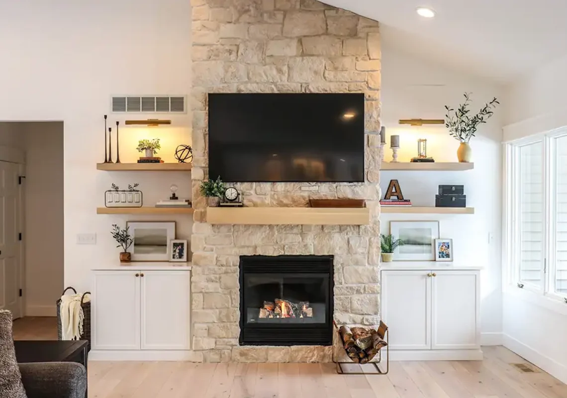 A beautiful family room with a large screen TV mounted onto a stonewall fireplace.